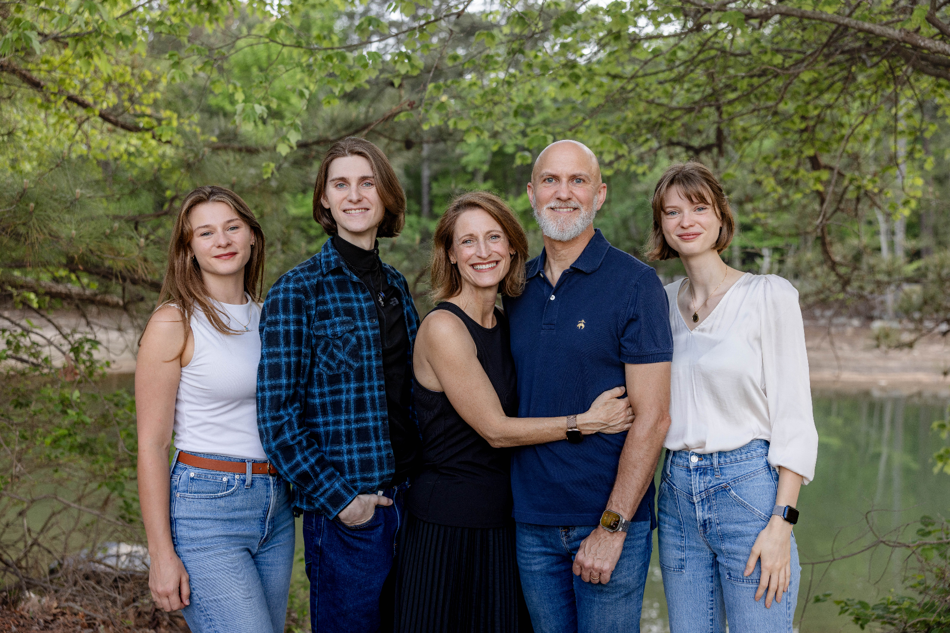 Family standing together outdoors by a lake