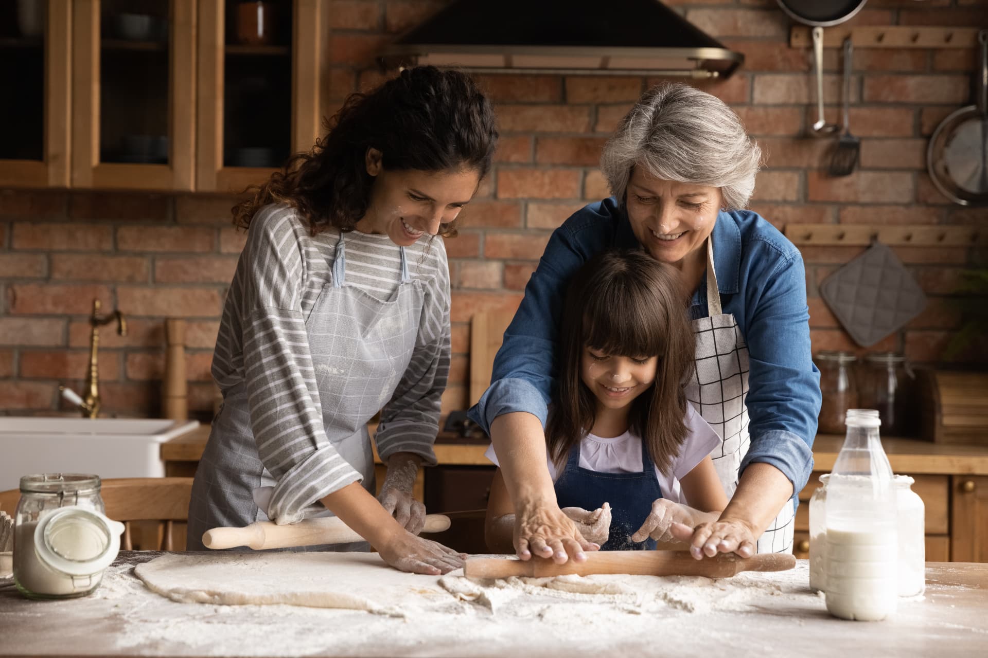 Three generations of smiling women baking together in a warm kitchen