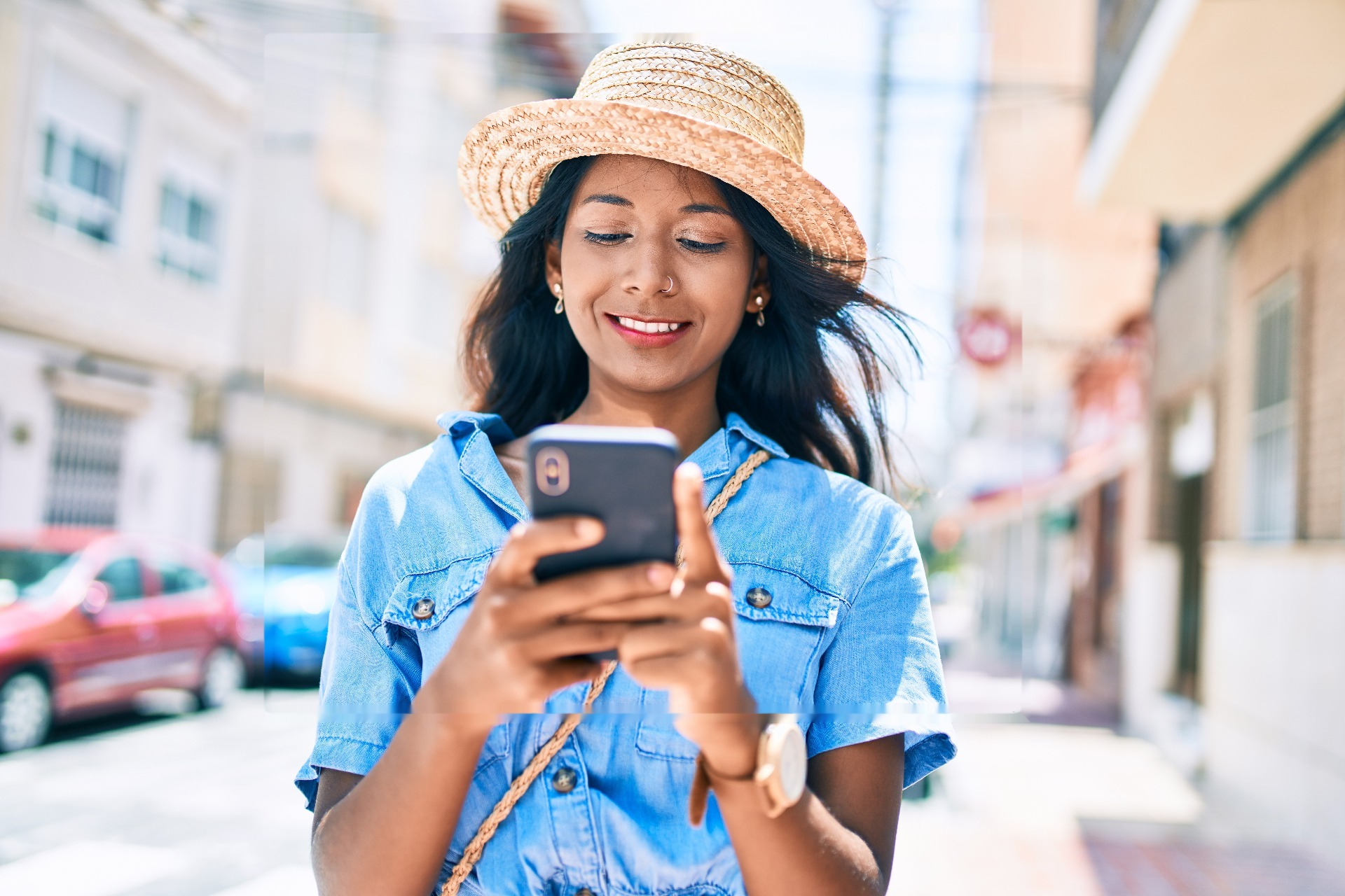 Young woman smiling while using her smartphone outdoors